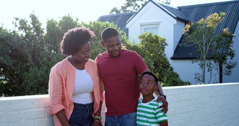 African american family standing together outside suburban home parents embracing son