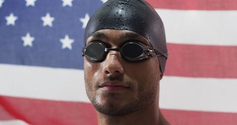 Confident Swimmer Posing with Determination in Front of American Flag
