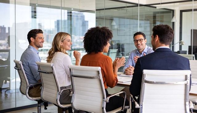 Business team applauding during meeting in modern glass conference room with skyline views