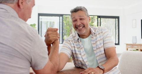 Middle-Aged Friends Joyfully Arm Wrestling in Modern Home