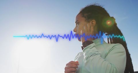 Fit woman listening to music with heartbeat graph overlay