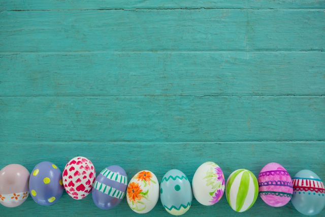 This image features a row of colorful painted Easter eggs on a green wooden background. Ideal for use in Easter-themed promotions, holiday greeting cards, festive event invitations, and spring decoration ideas. The vibrant colors and artistic designs make it perfect for adding a cheerful and festive touch to any project.