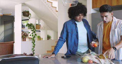 Friends Enjoying Healthy Produce and Technology in Modern Kitchen