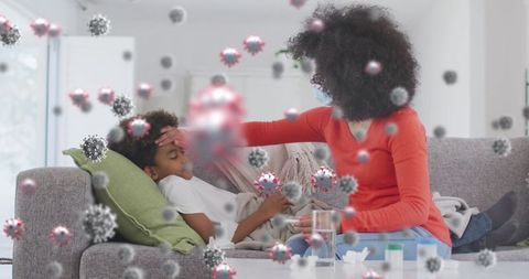 Mother wearing mask checking sick boy for fever indoors