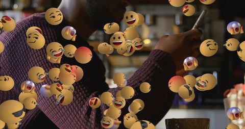 Man scrolling smartphone in cozy cafe surrounded by floating emoji reactions
