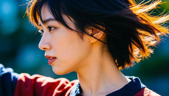 Sunlit side-profile portrait of asian woman with wind-blown hair and soft rimlighting