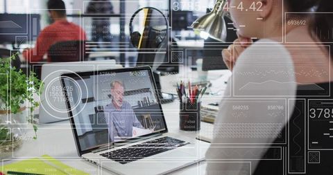 Young professional watching laptop during remote meeting in open office with HUD overlays