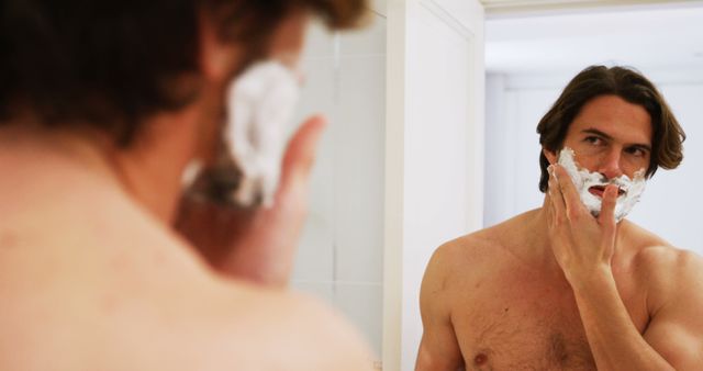 Young Man Shaving While Looking in Bathroom Mirror - Download Free Stock Images Pikwizard.com