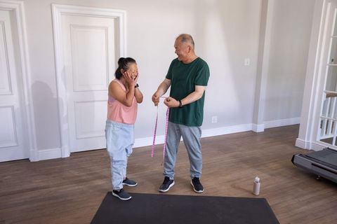 Senior chinese couple measuring fitness progress and laughing during home workout