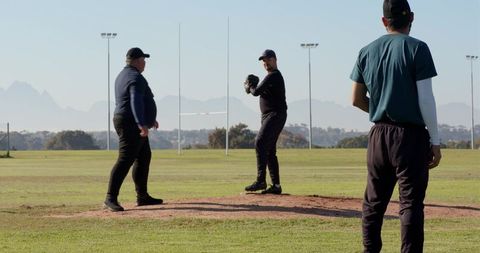 Baseball coach instructing pitcher on mound during outdoor team training session
