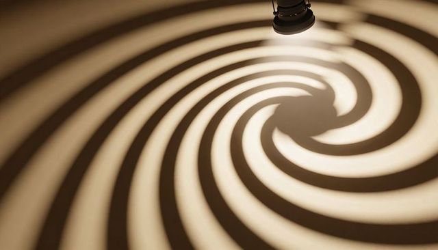 Sepia spiral gobo spotlight casting concentric rings rotating vortex stage projection art