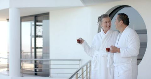 Senior Couple Enjoying Tea on Modern Balcony in Bathrobes