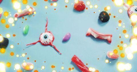 Gummy eyeball with licorice strands and vampire teeth candy with warm bokeh lights