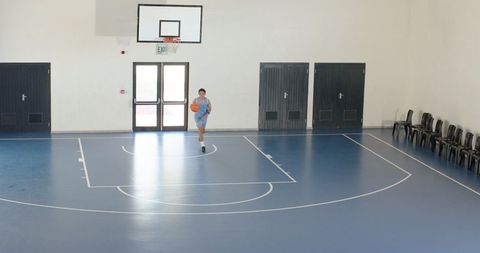 Athlete Dribbling Basketball Across Indoor Gym Court