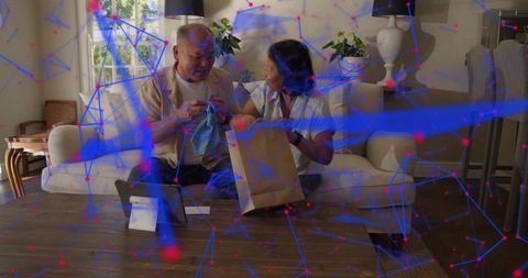 Senior couple unpacking online order, smiling and sharing discovery while using tablet