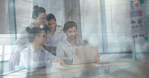 Business Team Collaborating Around Laptop in Modern Glass Office During Meeting
