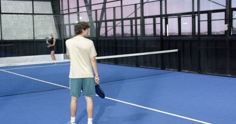 Evening Padel Game on Blue Court with Active Players