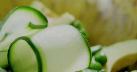 Thin cucumber ribbons on plate with green peas and squash