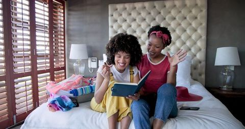 Diverse Female Couple Enjoying Book Together on Bed