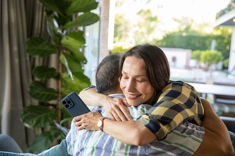 Senior couple embracing with smartphone in cozy living room