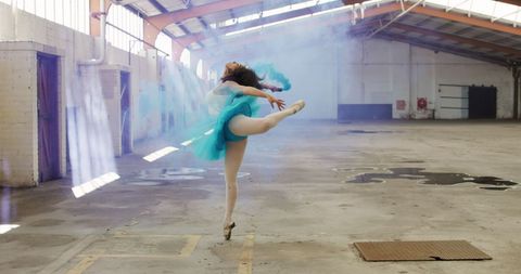Ballet dancer in abandoned warehouse with smoke flare