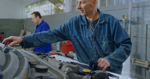 Mechanic wiping engine in workshop understanding automotive maintenance