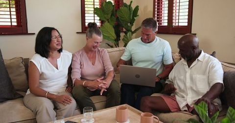 Diverse Group of Friends Sharing Ideas While Using Laptop in Cozy Living Room