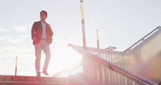 Young professional man in a suit walking up stairs in the morning city during sunrise. Perfect for projects illustrating determination, motivation, confidence, urban lifestyles, morning routines, or city life.