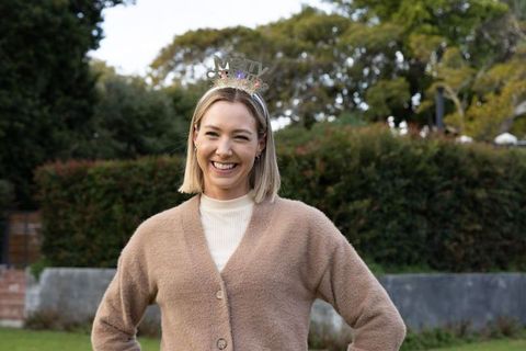Smiling woman wearing merry headband in garden celebrating festive holiday cheer