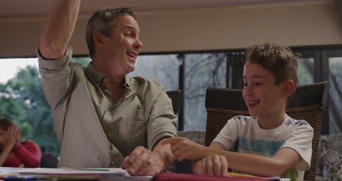 Father and Son Sharing High Five While Studying Together
