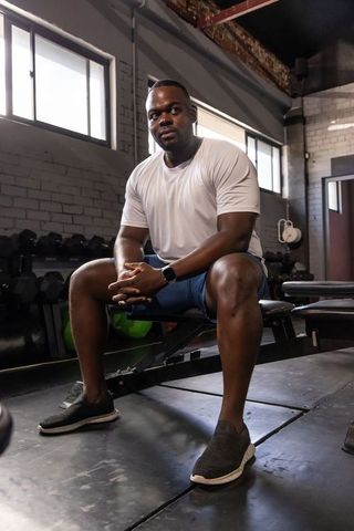 Man resting on bench in industrial gym wearing smartwatch and activewear