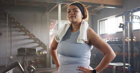 Confident african american woman standing in gym wearing towel and smartwatch post-workout