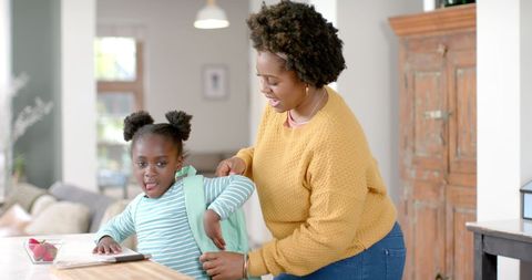 Happy Mother Helping Daughter Prepare for School at Home