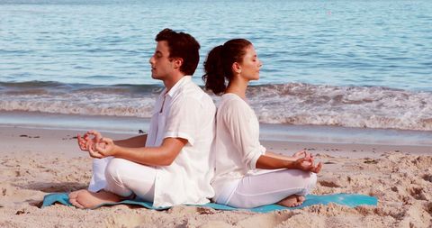 Couple Practicing Yoga Meditation on Serene Beach