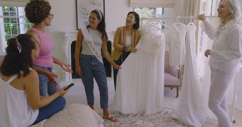 Bride-to-Be Choosing Wedding Dresses with Friends in Cozy Living Room