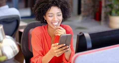 Happy Businesswoman Using Smartphone at Work Desk