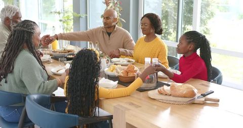 Multigenerational Black Family Holding Hands Around Dining Table Sharing Meal