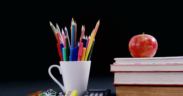 Colorful Desk Supplies and Apple on Book Stack Against Black Background - Download Free Stock Images Pikwizard.com