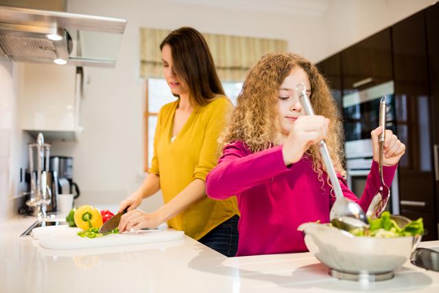 Mother and daughter working in kitchen at home