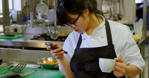 Chef Using Smartphone While Relaxing in Commercial Kitchen