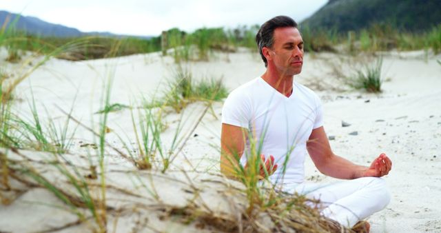 Middle-aged man meditating on sandy beach to find inner peace - Download Free Stock Images Pikwizard.com