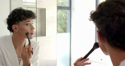 Man practicing makeup routine in modern bathroom mirror