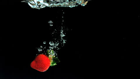 Fresh Strawberry Submerging in Clear Water with Bubbles