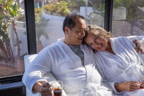 Senior Couple in Bathrobes Relaxing in Sunlit Room with Tea