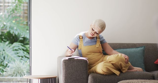 Young Woman Relaxing on Couch and Writing in Notebook - Download Free Stock Images Pikwizard.com