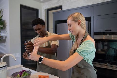 Smiling couple cooking salad in modern kitchen