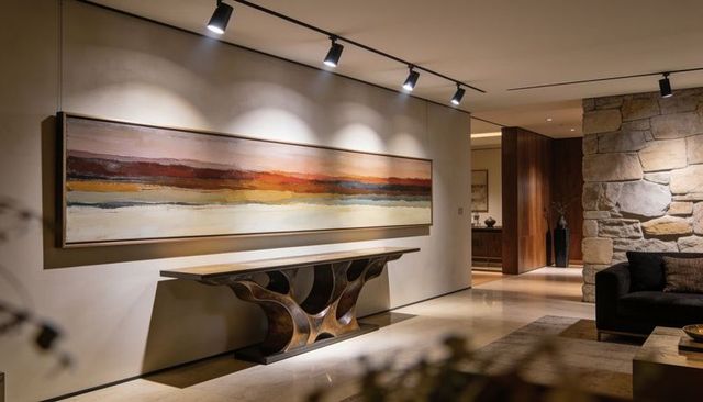Showcasing horizontal abstract painting above sculptural console in modern luxury entryway