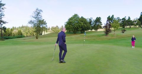 Golf partners on green lining up putts