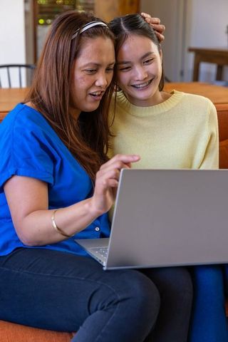 Mother and Teenage Daughter Using Laptop at Home