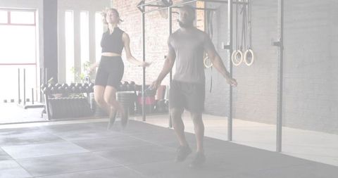 Training partners jumping rope together in industrial gym during high-intensity cardio workout
